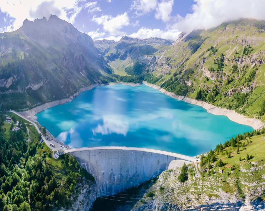 Water dam and reservoir lake in Swiss Alps mountains producing sustainable hydropower, hydroelectricity generation, renewable energy to limit global warming, aerial view, decarbonize, summer